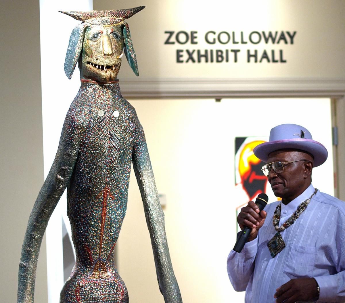 Sculpture in Zoë Galloway Exhibit Hall beside a man speaking into a microphone