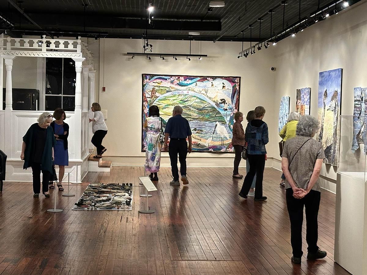 People viewing large colorful artworks in a gallery with polished wood floors