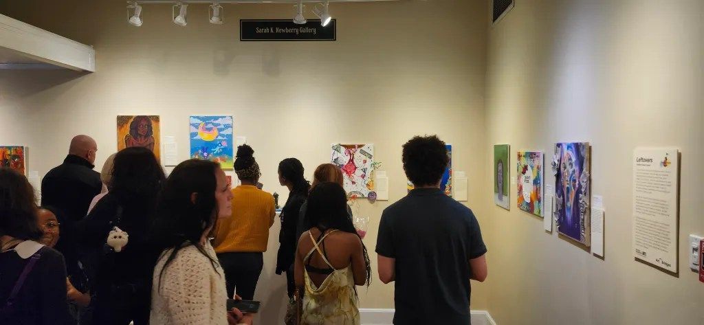 Visitors viewing colorful artwork in a gallery exhibition.