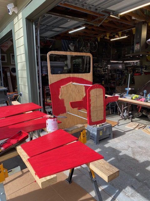Red-painted wooden panels and a small cart frame in a garage workshop under construction.