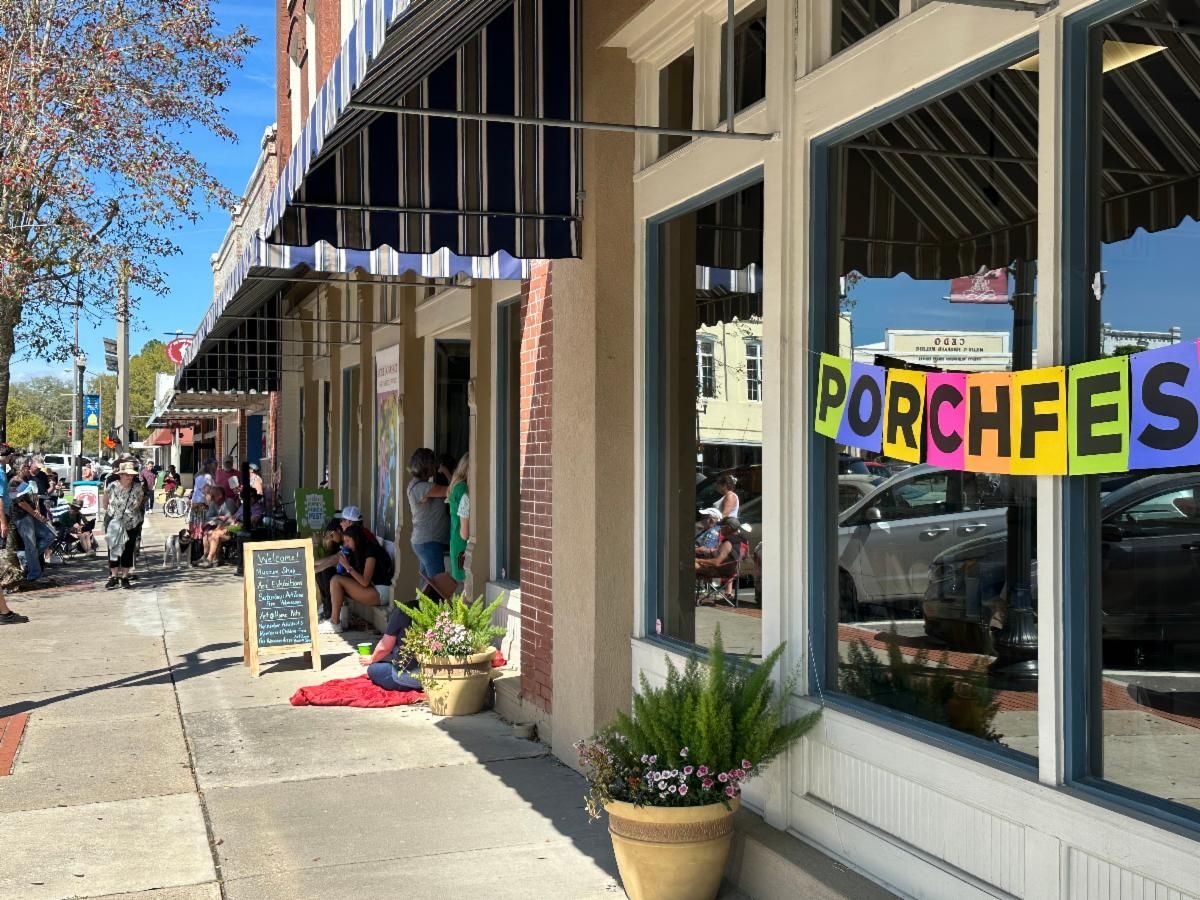 Storefront with colorful “PORCHEES” sign, potted plants, and sidewalk display on a sunny street