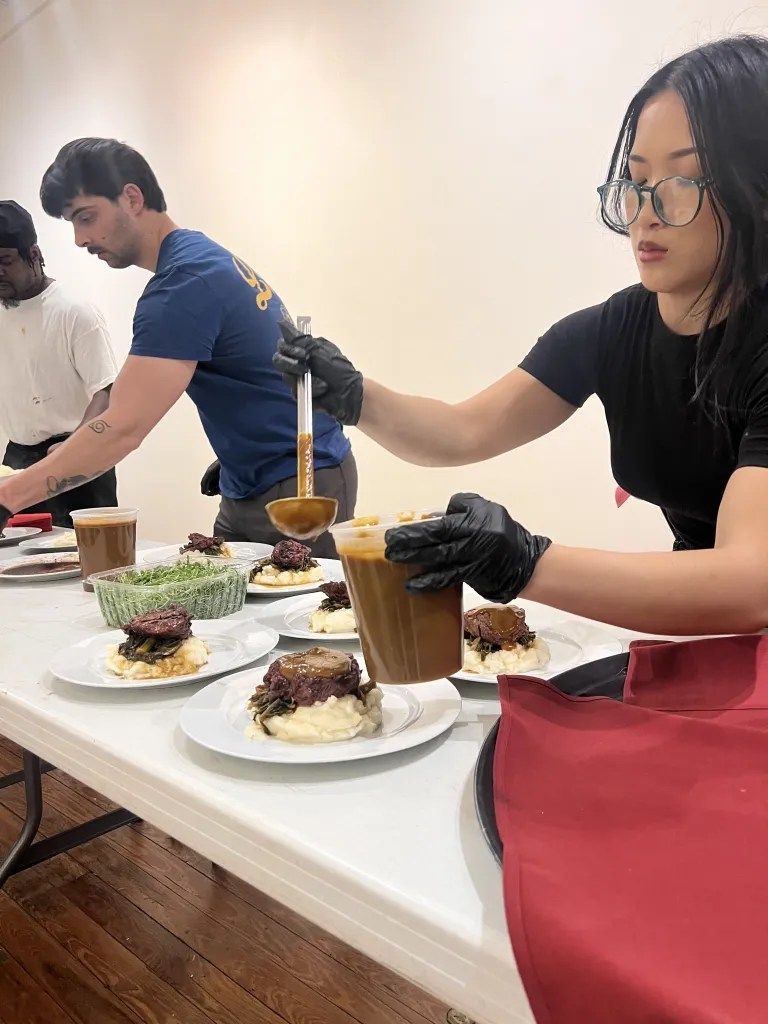 People arranging plated desserts on a table at a food event