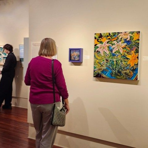 Art gallery opening with guests viewing colorful paintings on a wall