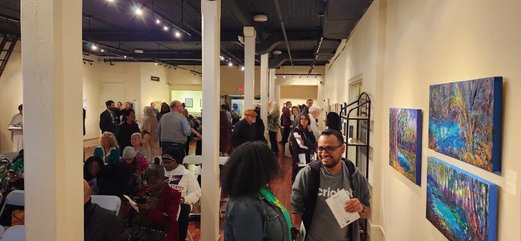 Art gallery exhibition with people viewing colorful paintings in a bright indoor space