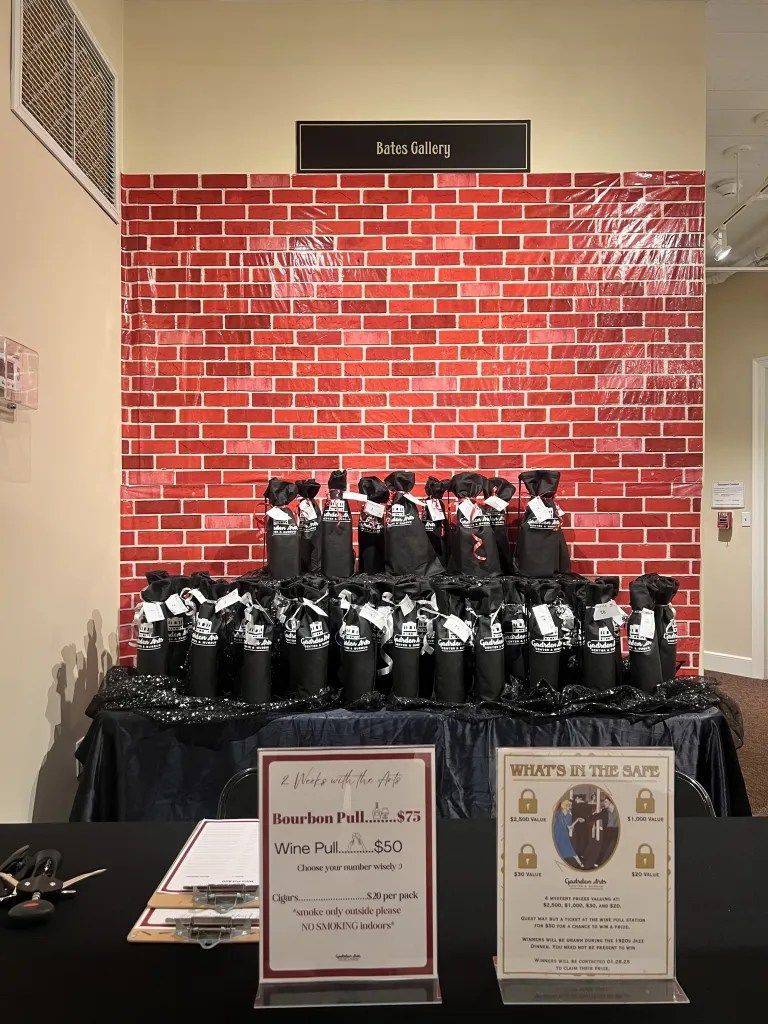 Display of black items on a table against a red brick backdrop, with small signs and a doorway above.