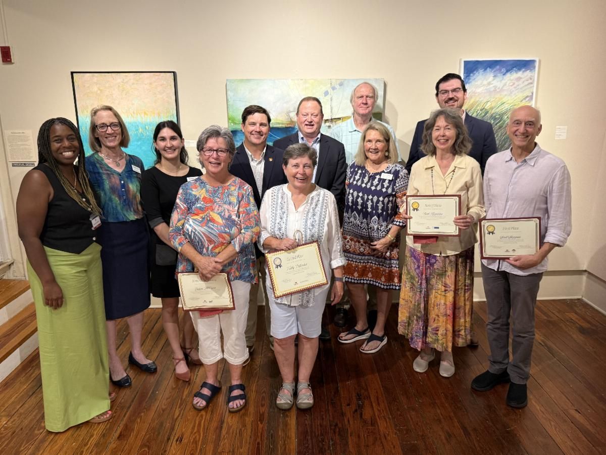 Group of people posing indoors, several holding framed certificates in a conference room