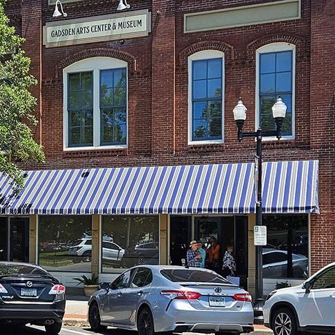 Brick storefront with blue-and-white striped awning and parked cars on the street