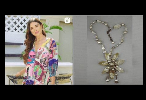 Woman in colorful floral dress beside a silver floral pendant necklace on a gray background