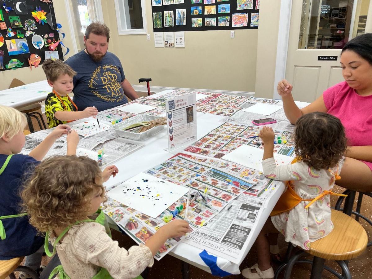 Family working on a large board game at a table in a bright room
