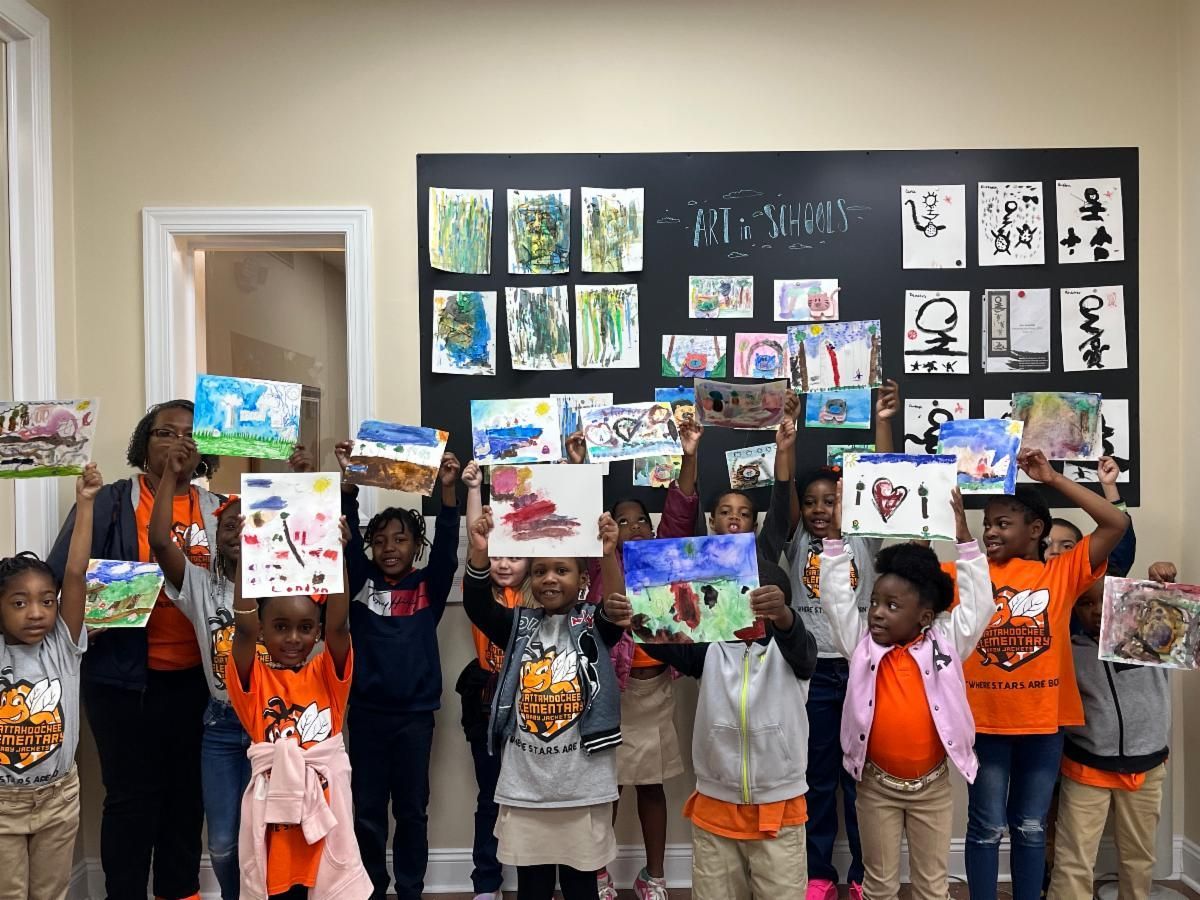 Children holding up colorful artwork in a classroom display, with drawings and collages on the wall.