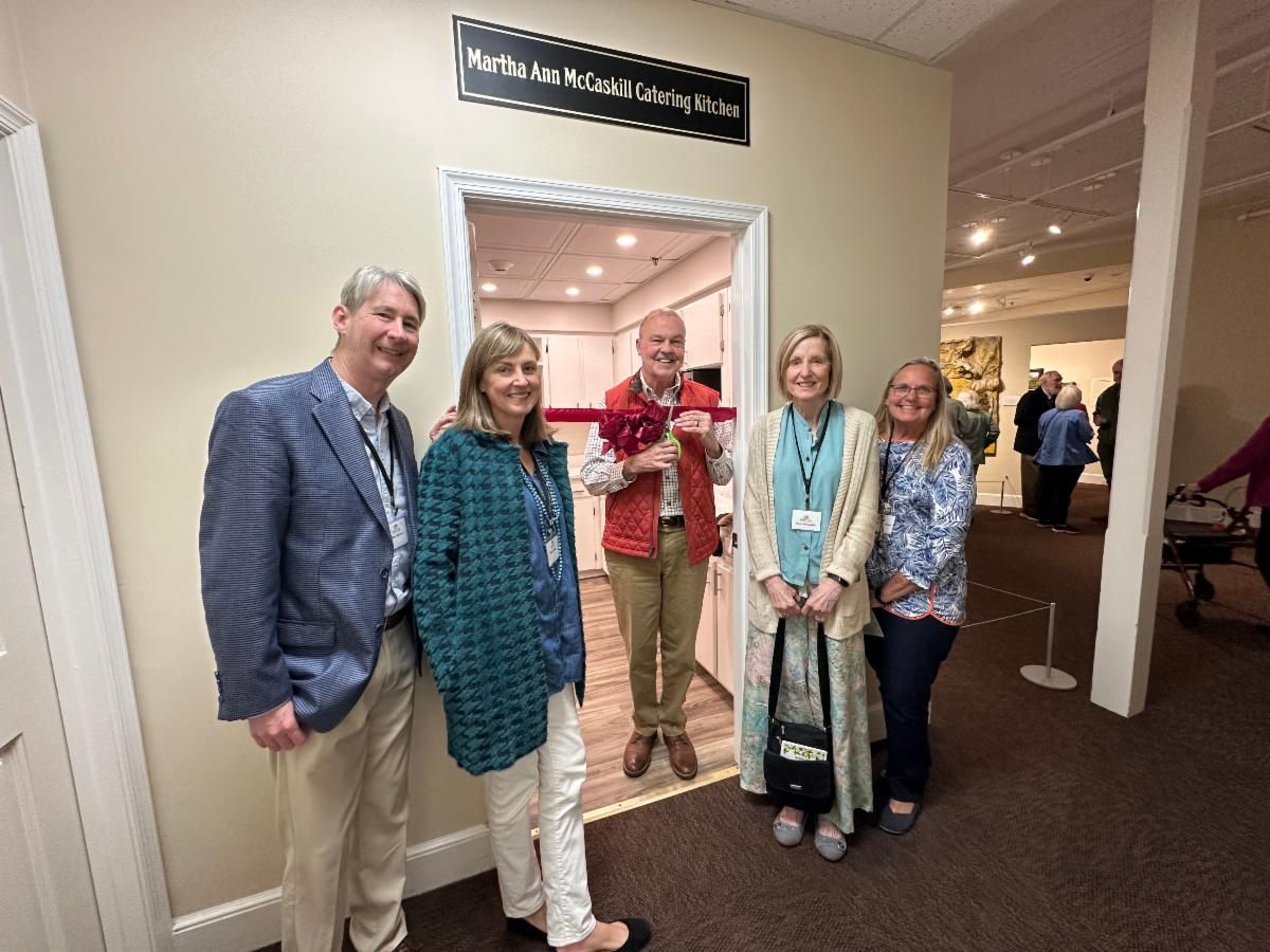Five people posing in a hotel hallway by a doorway, smiling at the camera.