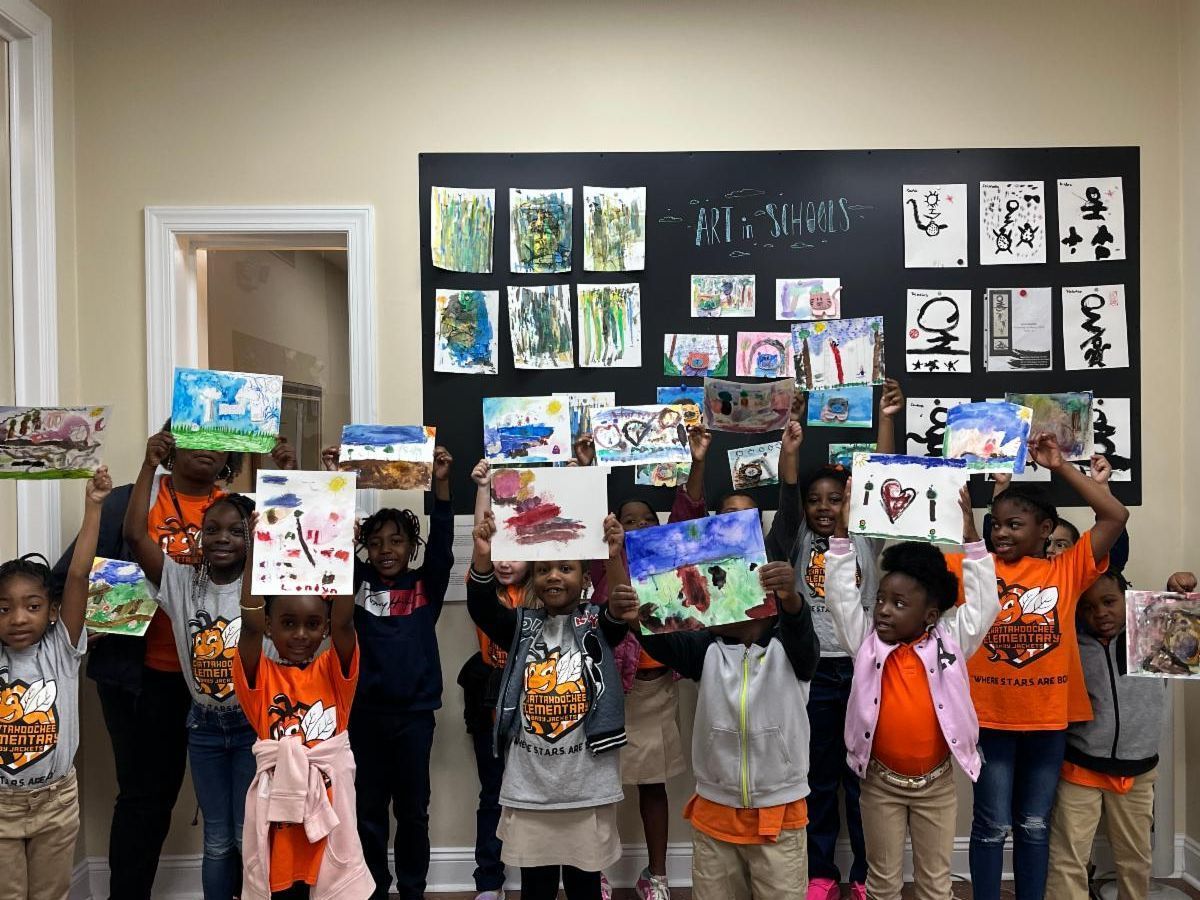Children holding up colorful drawings in a classroom display area