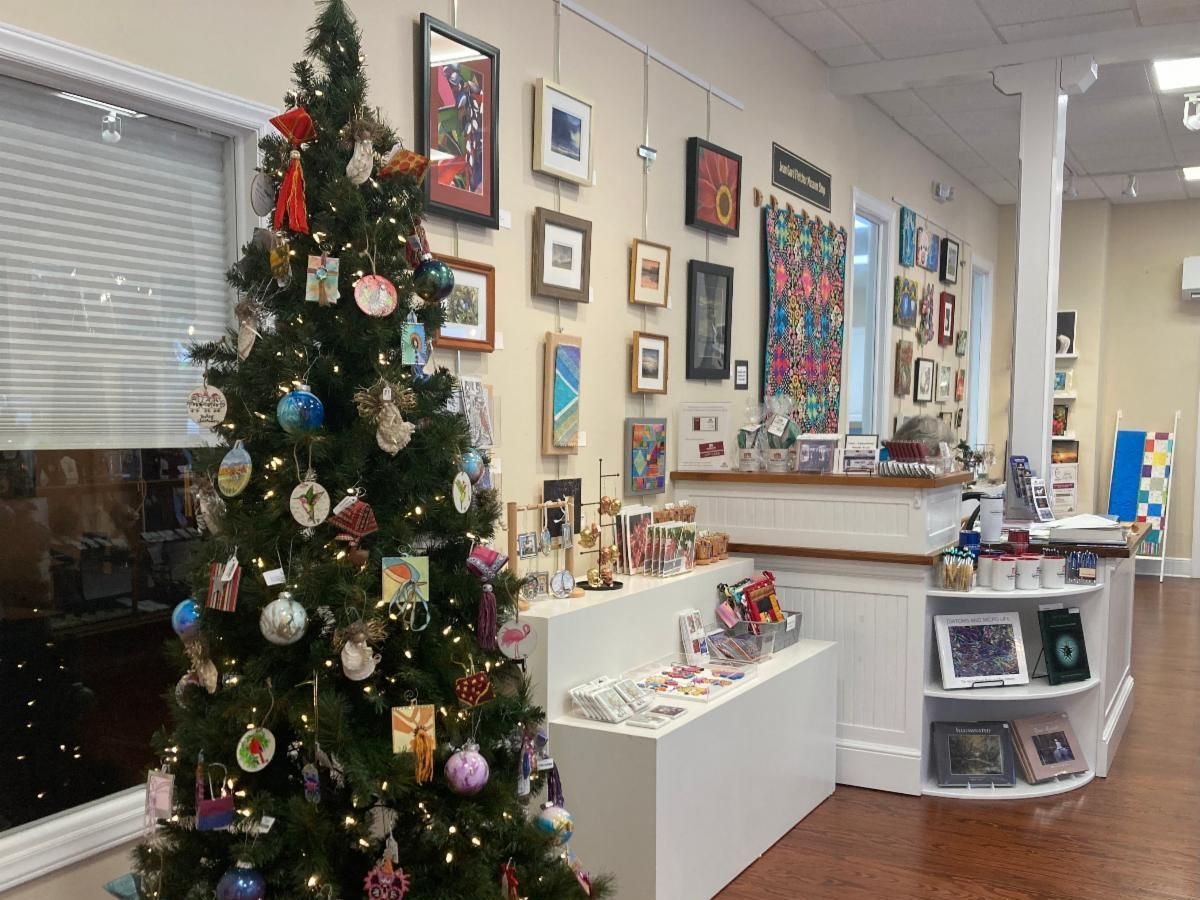 Holiday-decorated lobby with a Christmas tree, framed artwork, and display shelves