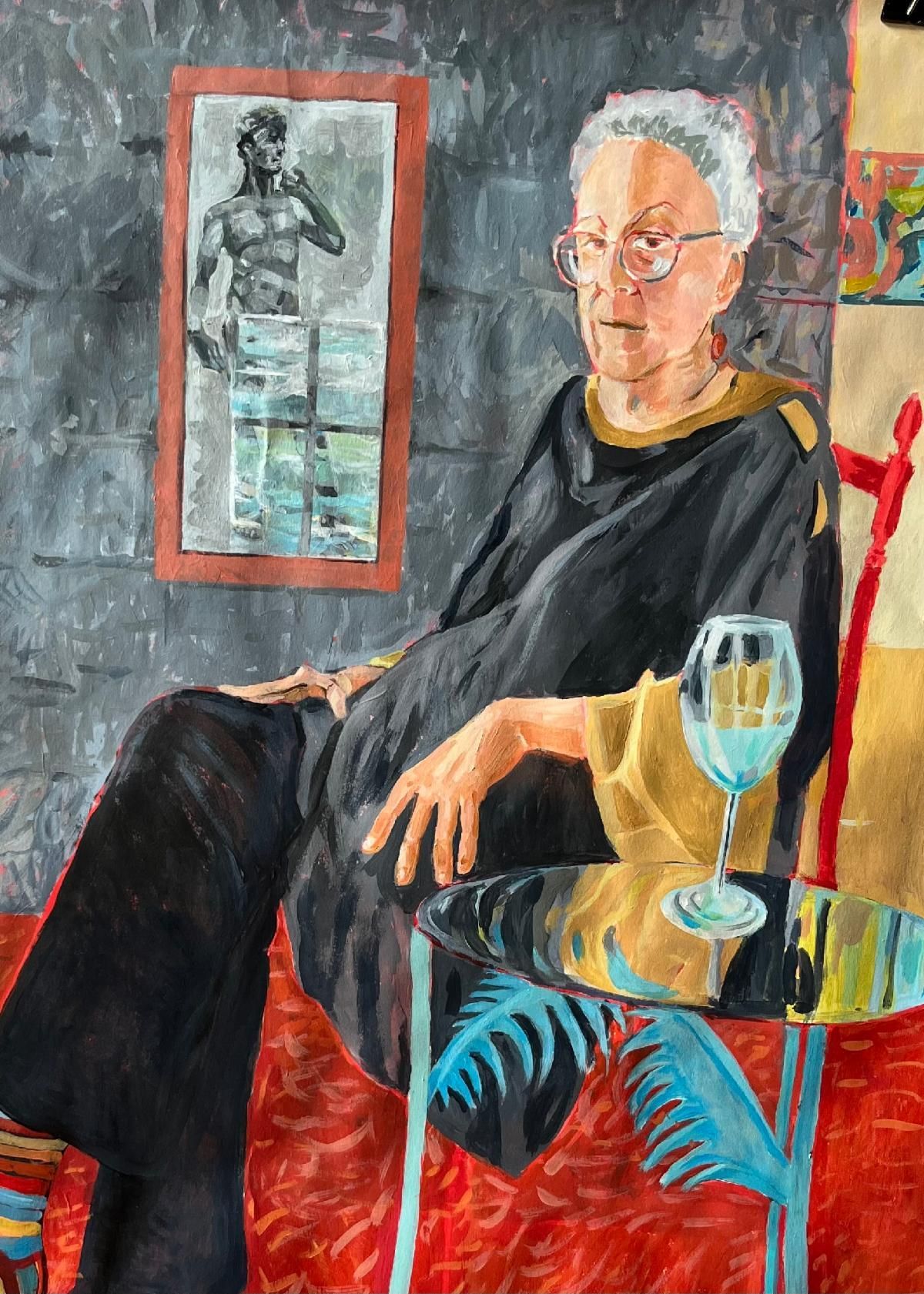 Seated man in a black shirt in a colorful painted interior, with a wine glass on a small table.