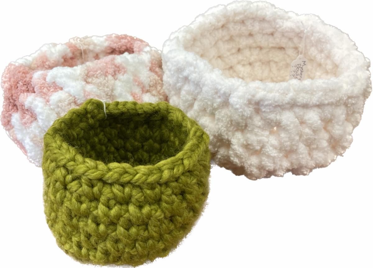 Three crocheted yarn baskets in green, cream, and pink-white