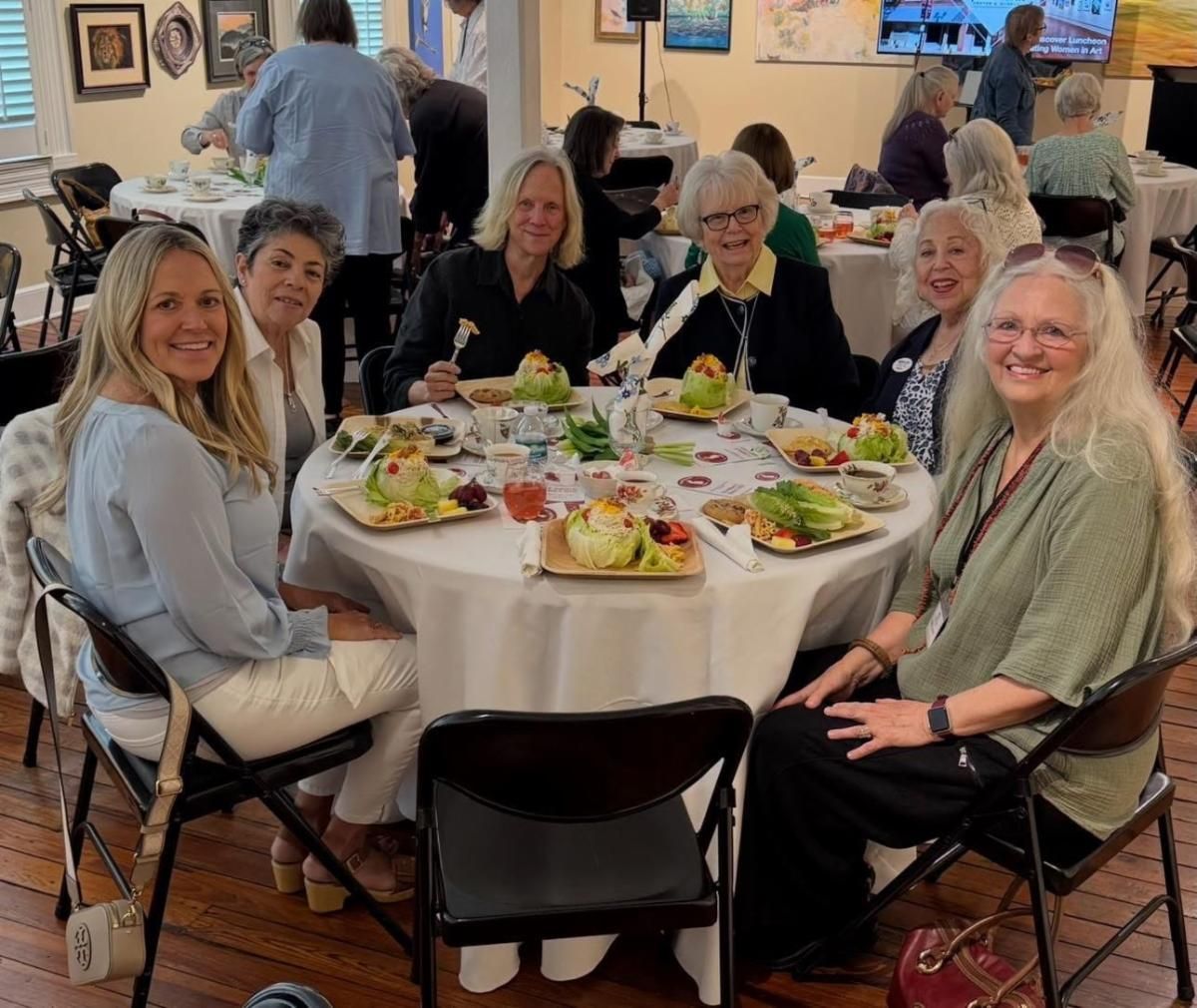 Friends seated around a table with salads and drinks at a casual indoor gathering
