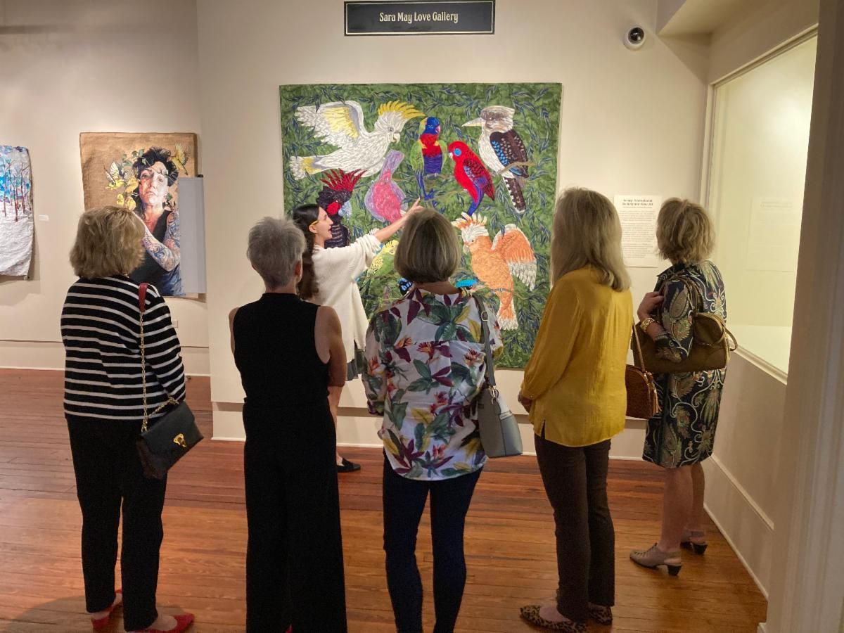 Visitors viewing colorful artwork in a gallery, seen from behind.