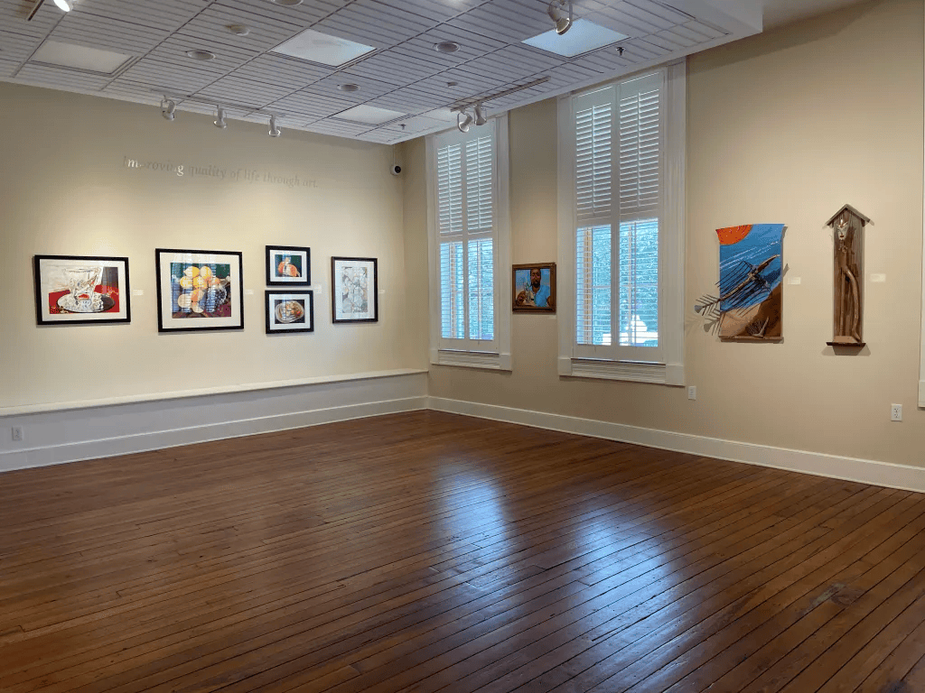 Empty art gallery with framed paintings on white walls and a polished wood floor