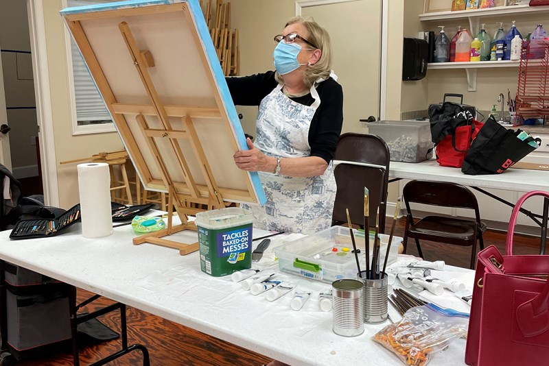 Woman painting at an easel in a classroom art workshop