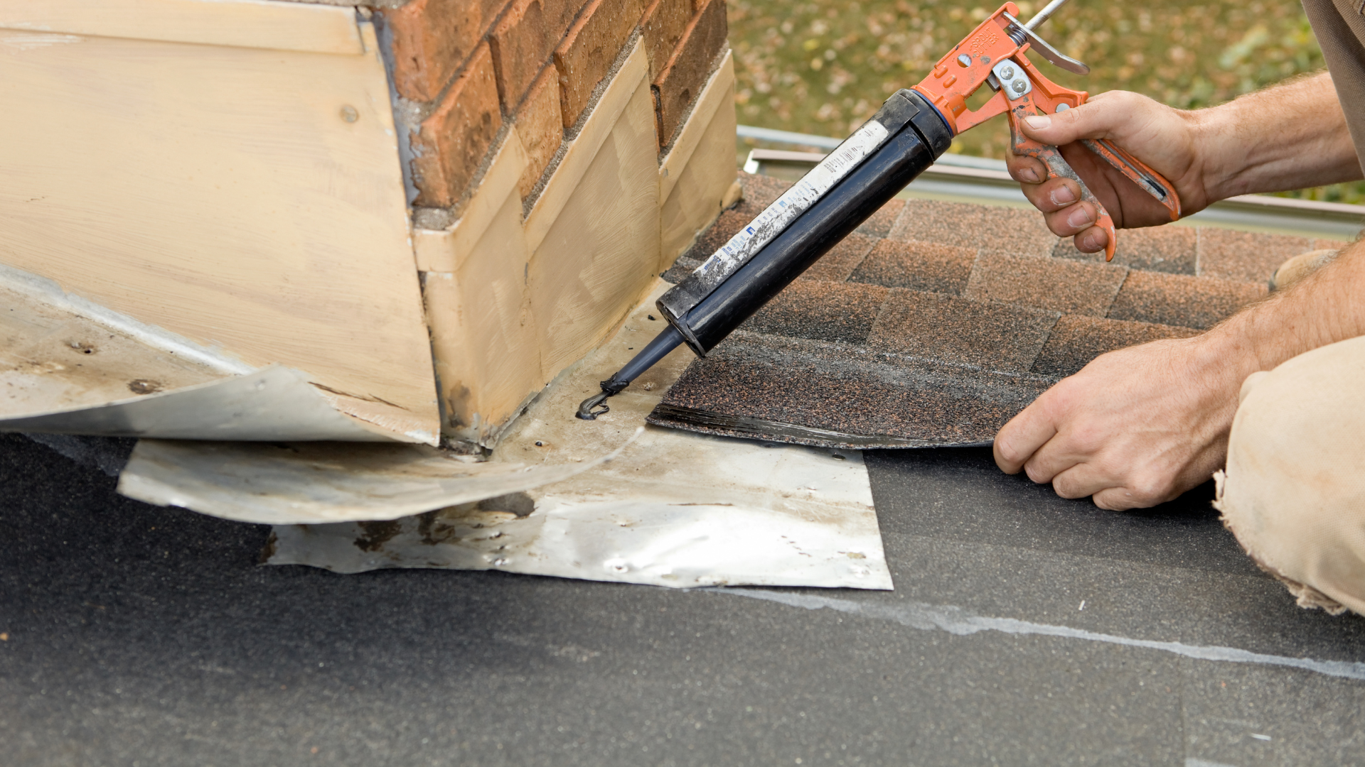 Worker applying sealant around a roof vent with a caulking gun on a flat roof