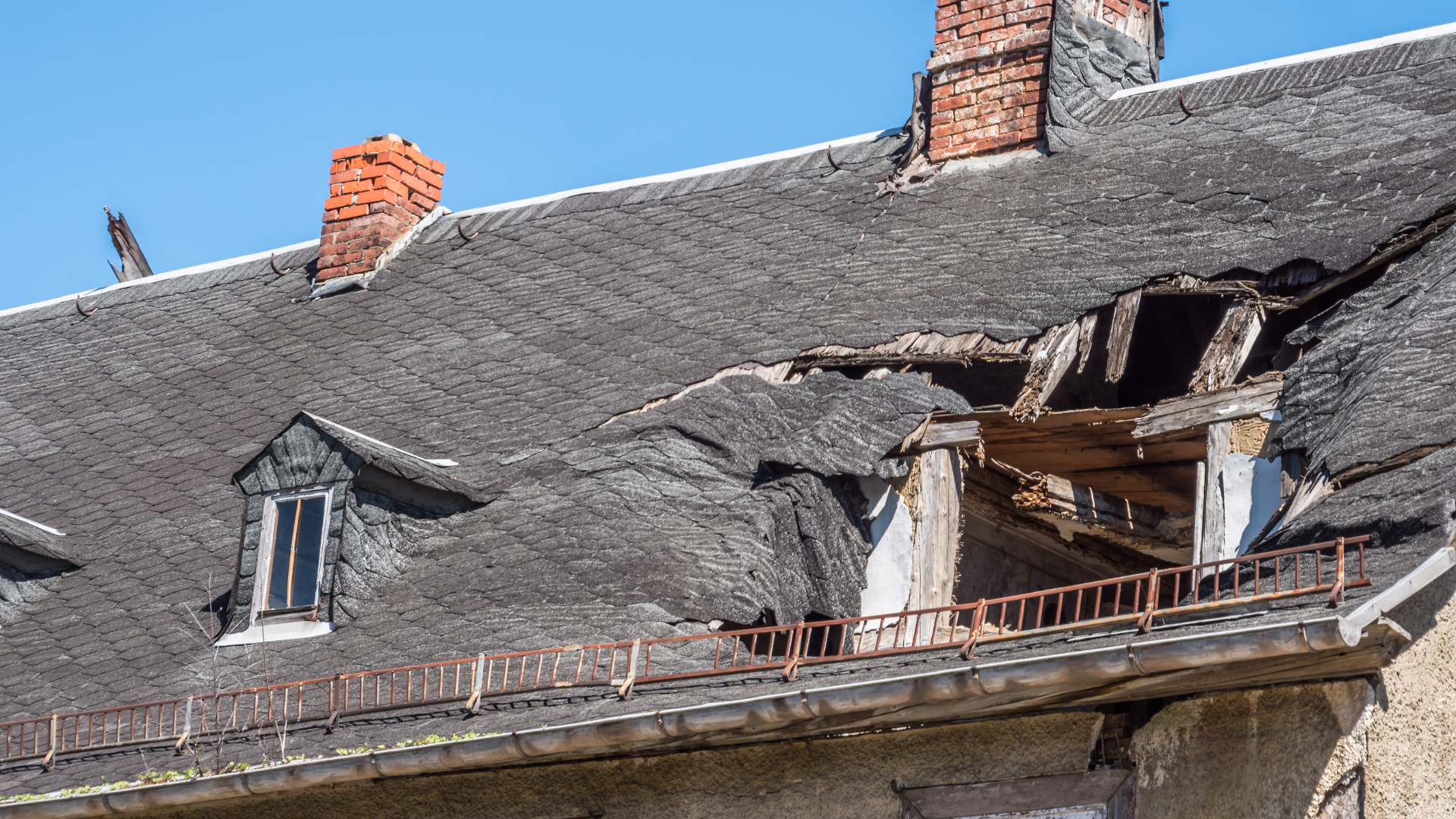 Damaged roof with a large hole and broken tiles on an old building