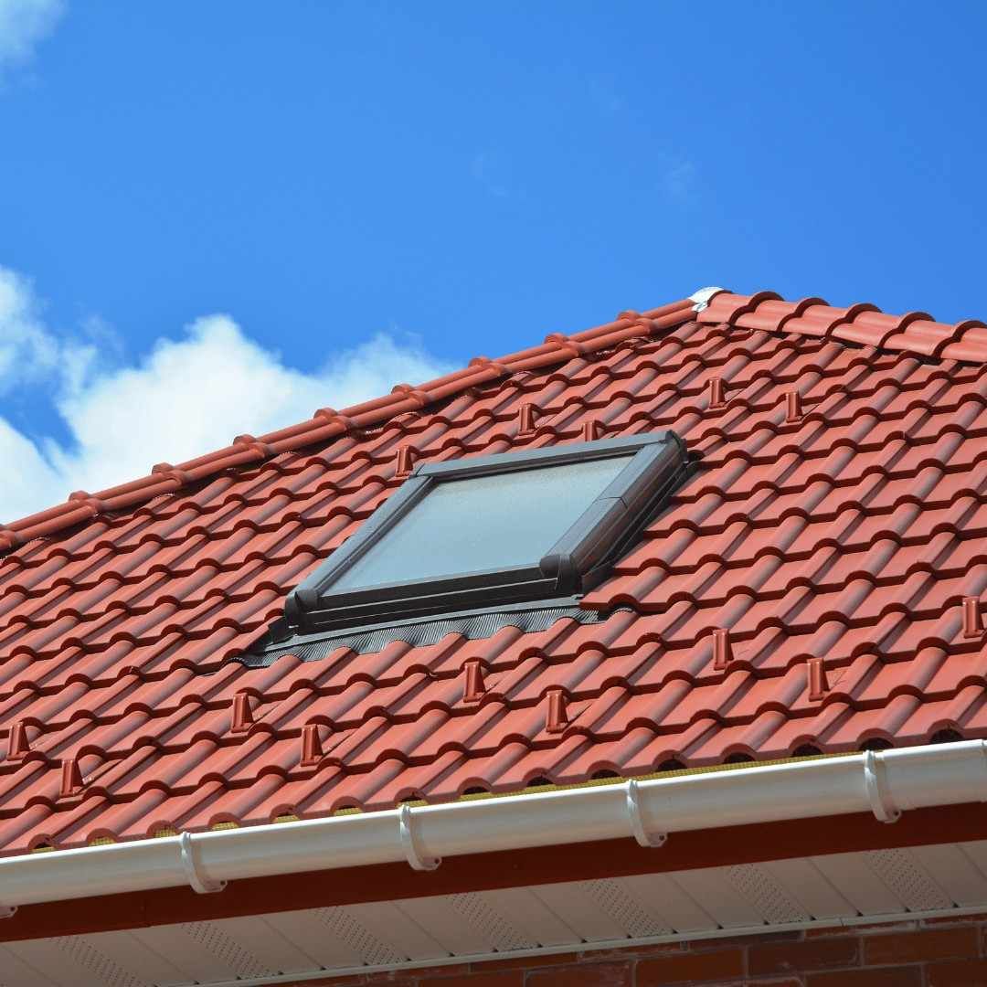 Red tiled roof with a skylight under a blue sky