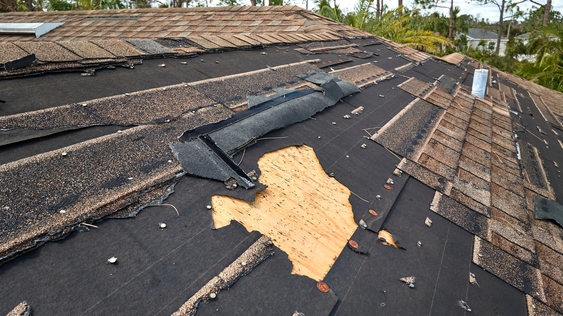 Damaged roof with missing shingles and exposed underlayment after storm damage