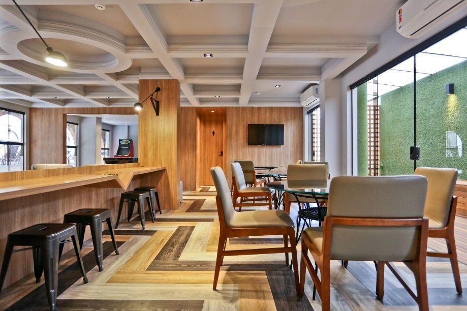 Interior moderno de café, com mesas, bancos, cadeiras de madeira e janelas amplas