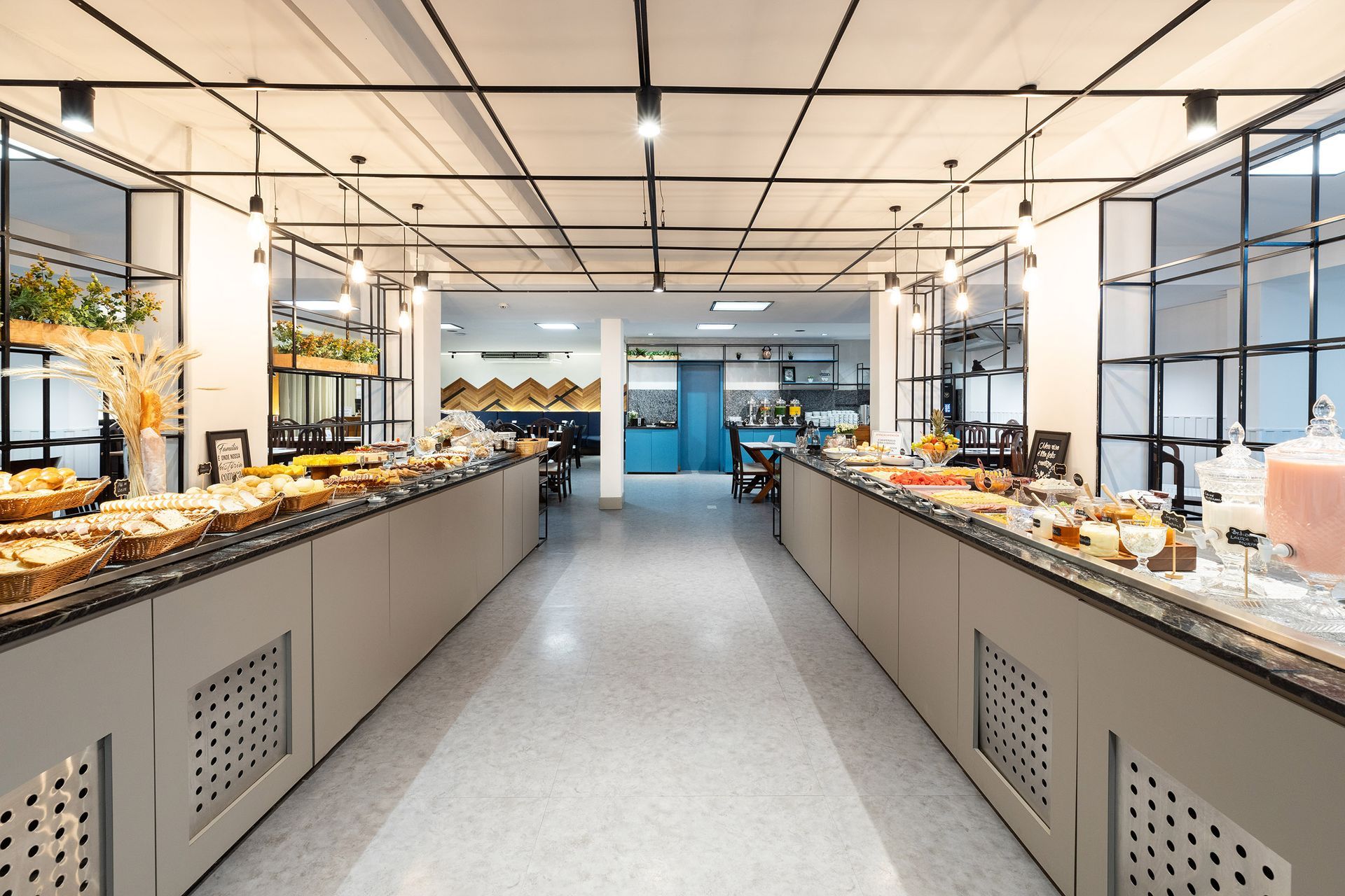 Buffet de hotel luminoso, com longos balcões de serviço e pastelaria, numa sala de refeições moderna e banhada pelo sol