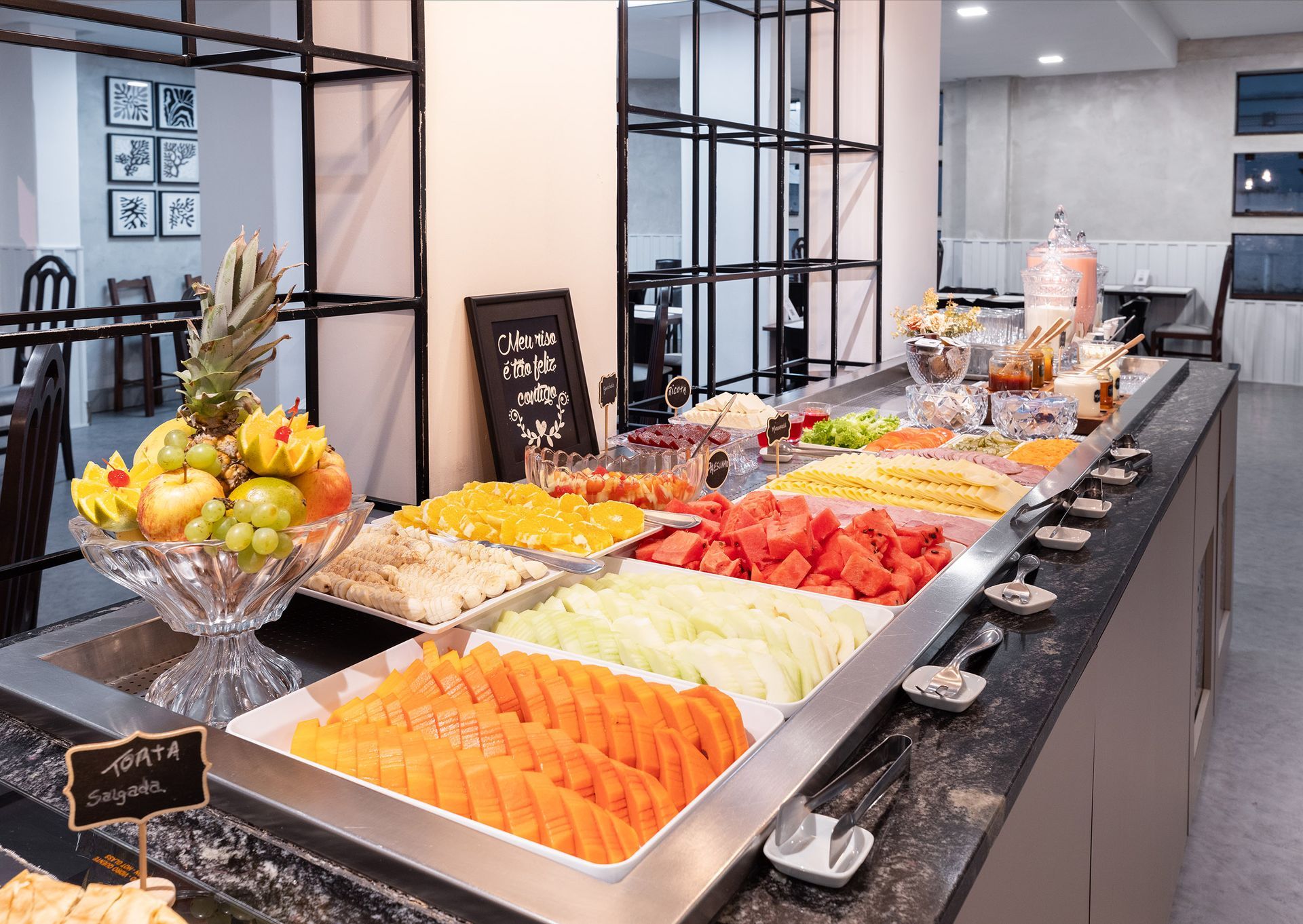 Buffet de frutas e sobremesas em um balcão comprido numa sala de jantar moderna