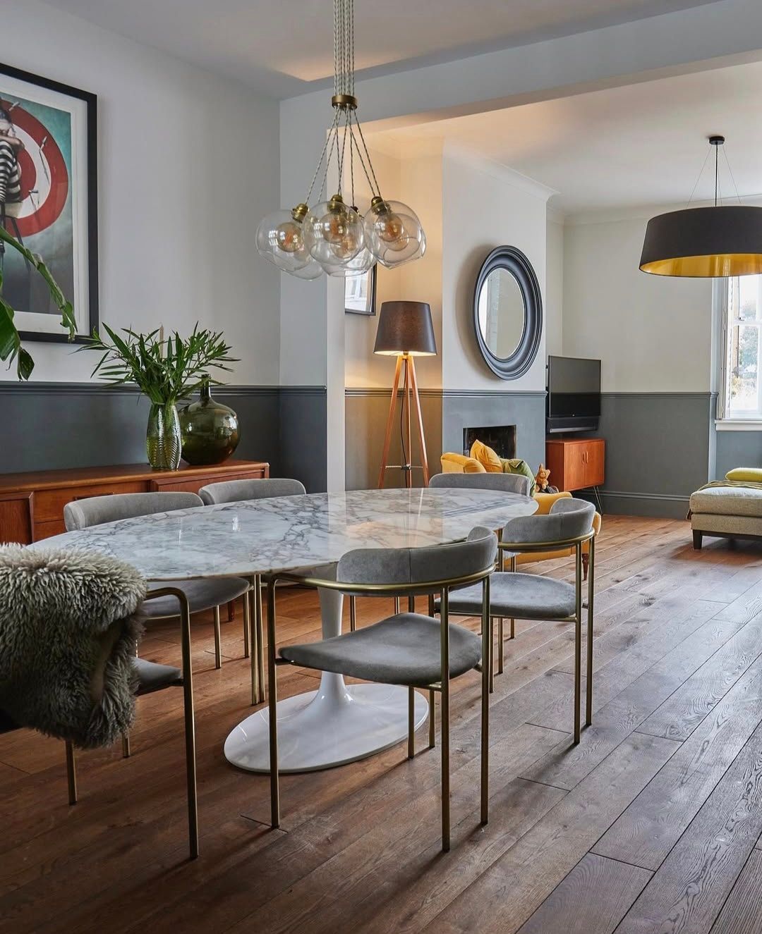Dining room with marble table, gray chairs, and modern lighting.