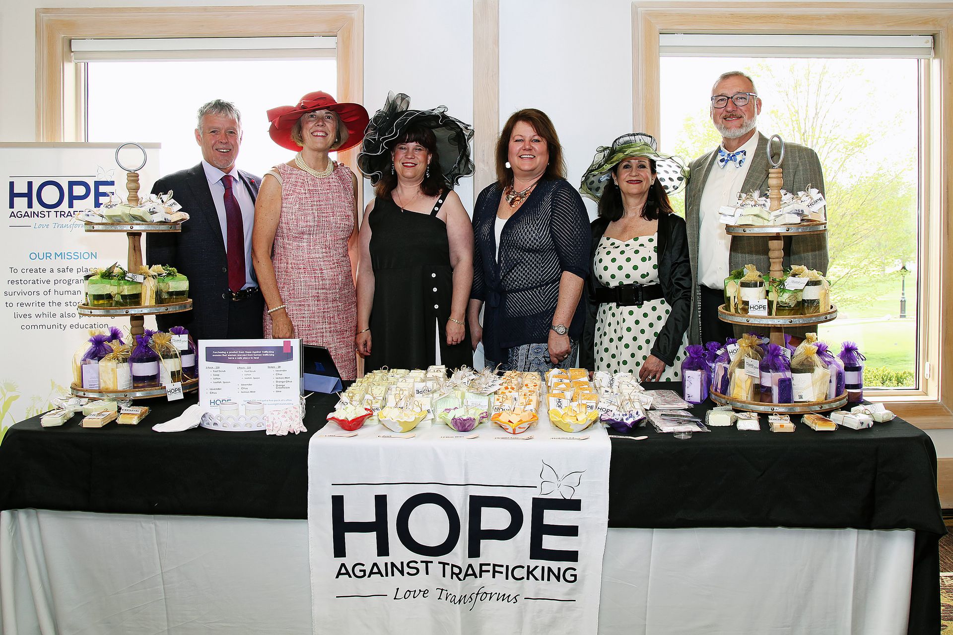 A group of people are posing for a picture in front of a table with a sign that says hope against trafficking.