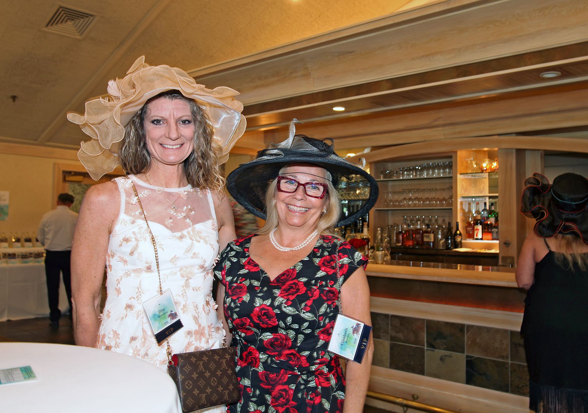 Two women wearing hats and dresses are posing for a picture.