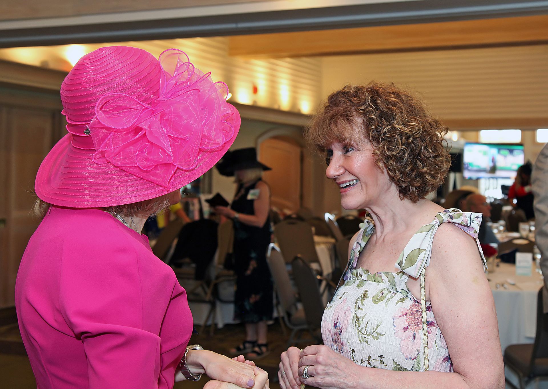 Two women wearing pink hats are talking to each other