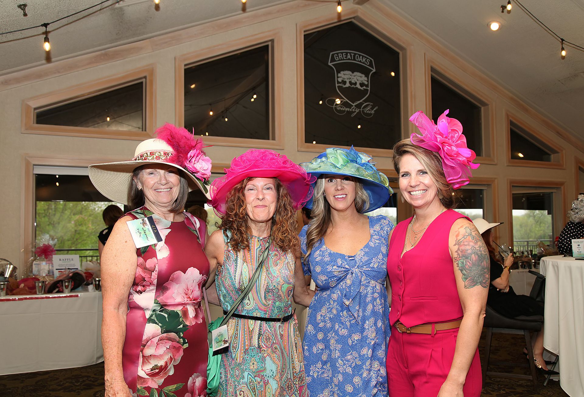 A group of women wearing hats and dresses are posing for a picture.