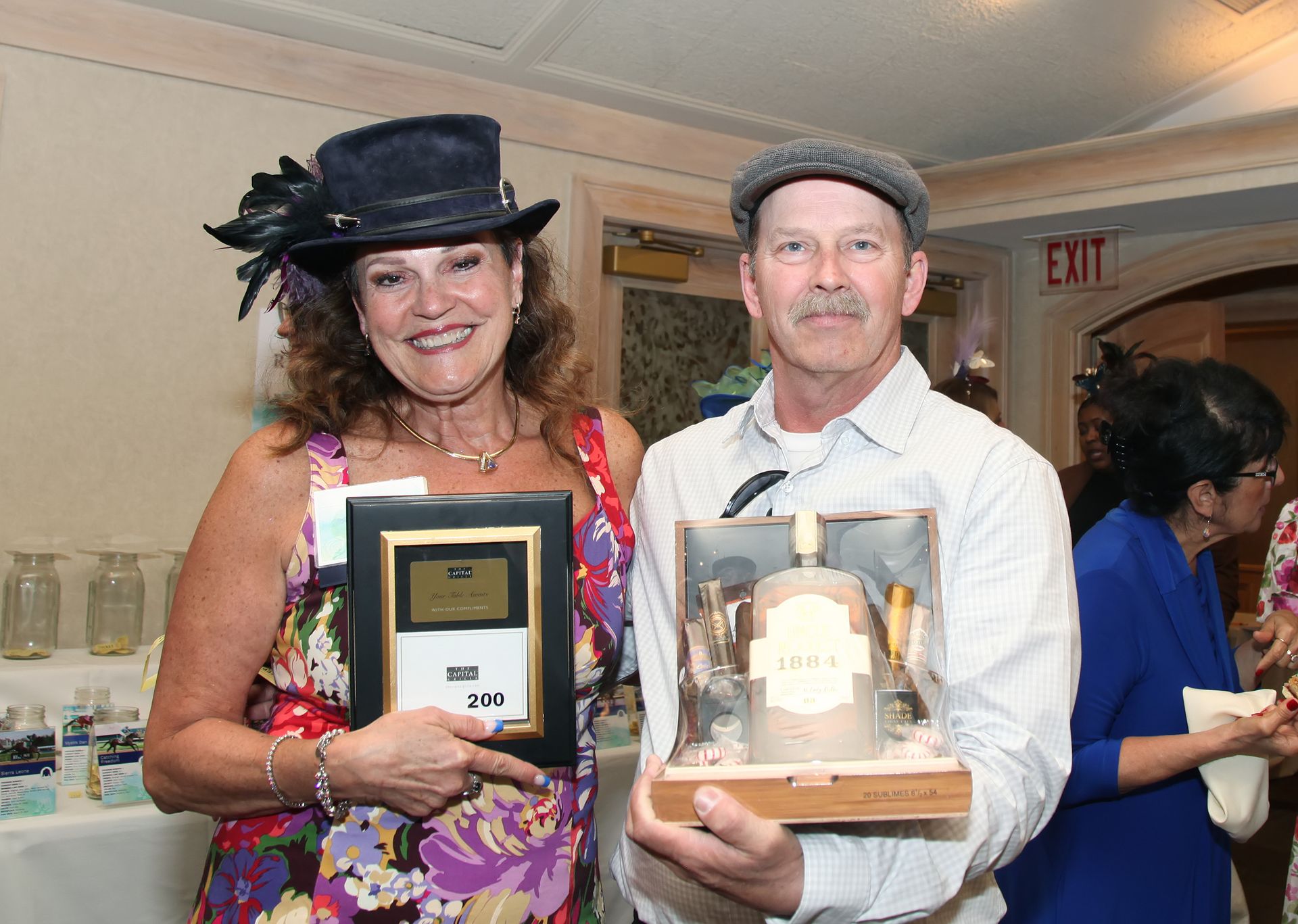 A man and a woman are posing for a picture while holding awards.