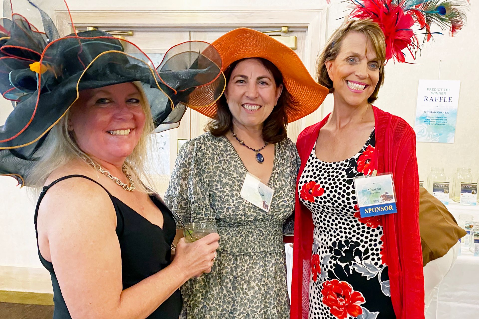 Three women wearing hats and dresses are posing for a picture.