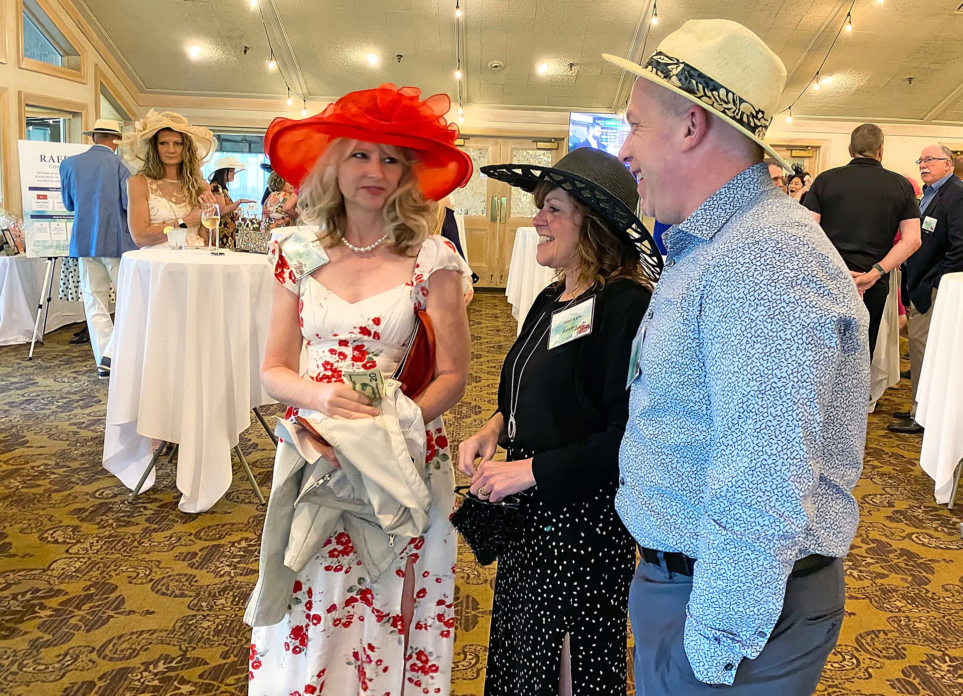 A group of people are standing in a room talking to each other.