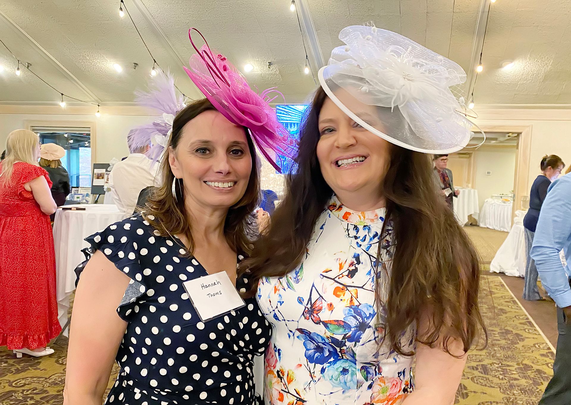 Two women wearing hats are posing for a picture in a room.
