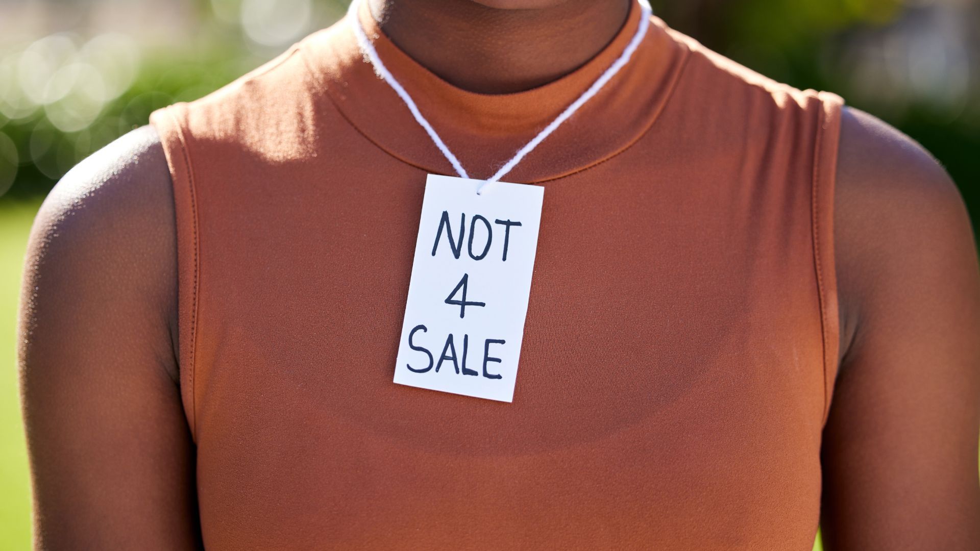 A woman is wearing a tag around her neck that says `` not 4 sale ''.