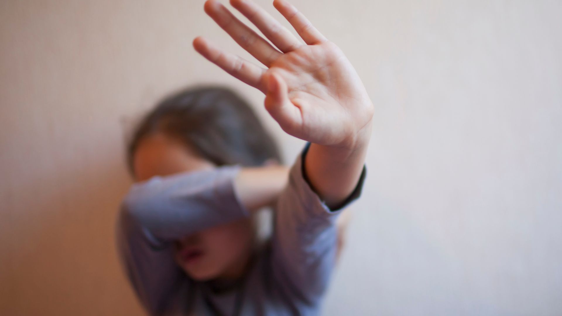 A young girl is covering her face with her hand.