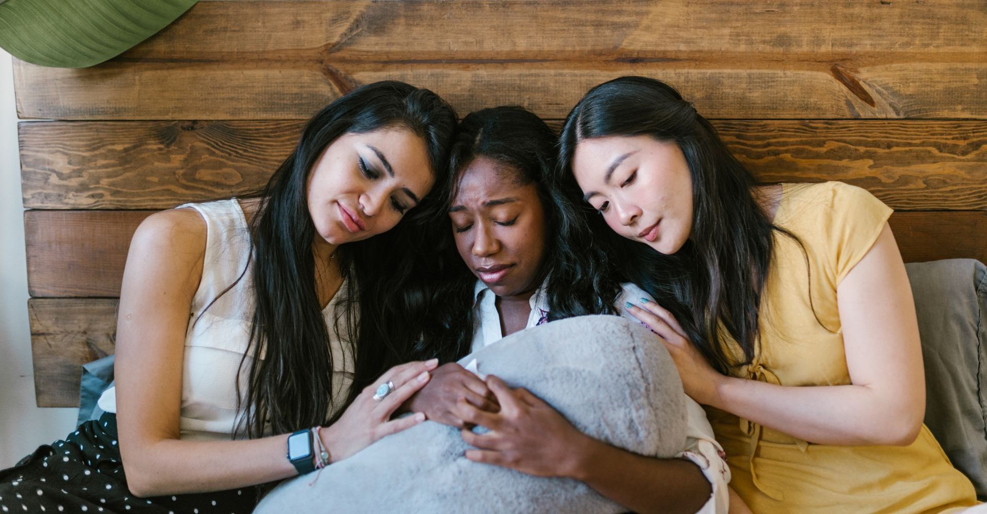 Three women are hugging each other on a bed.