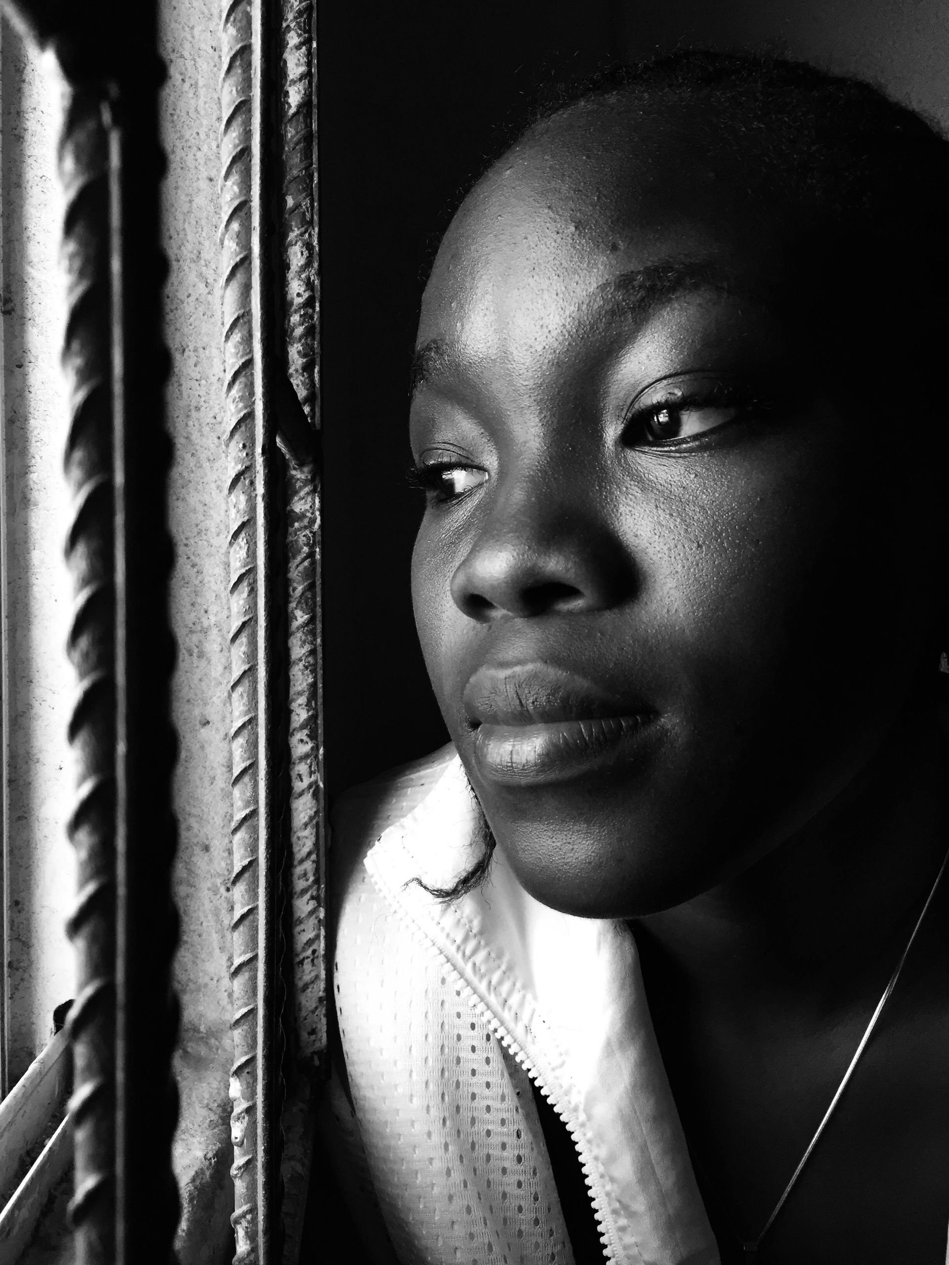 Person gazing out a window in soft black-and-white light