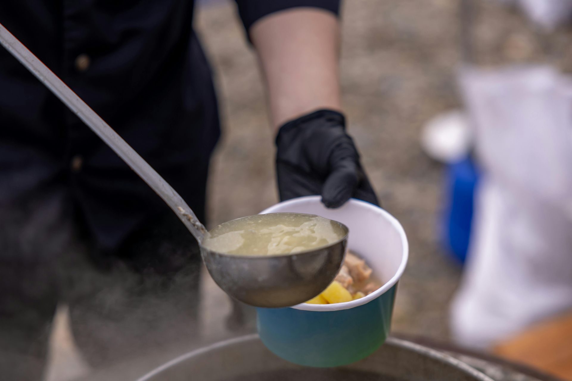 A person is pouring soup into a cup with a ladle.