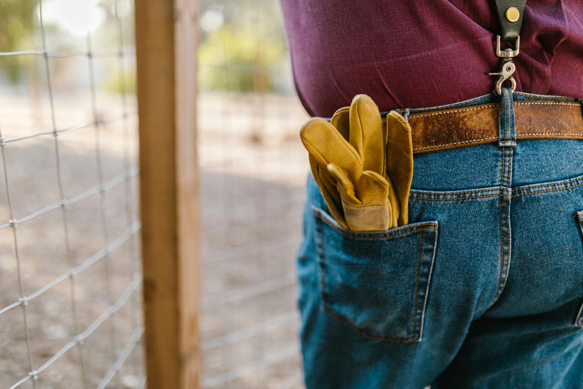 A working man is holding a pair of gloves in his pocket.