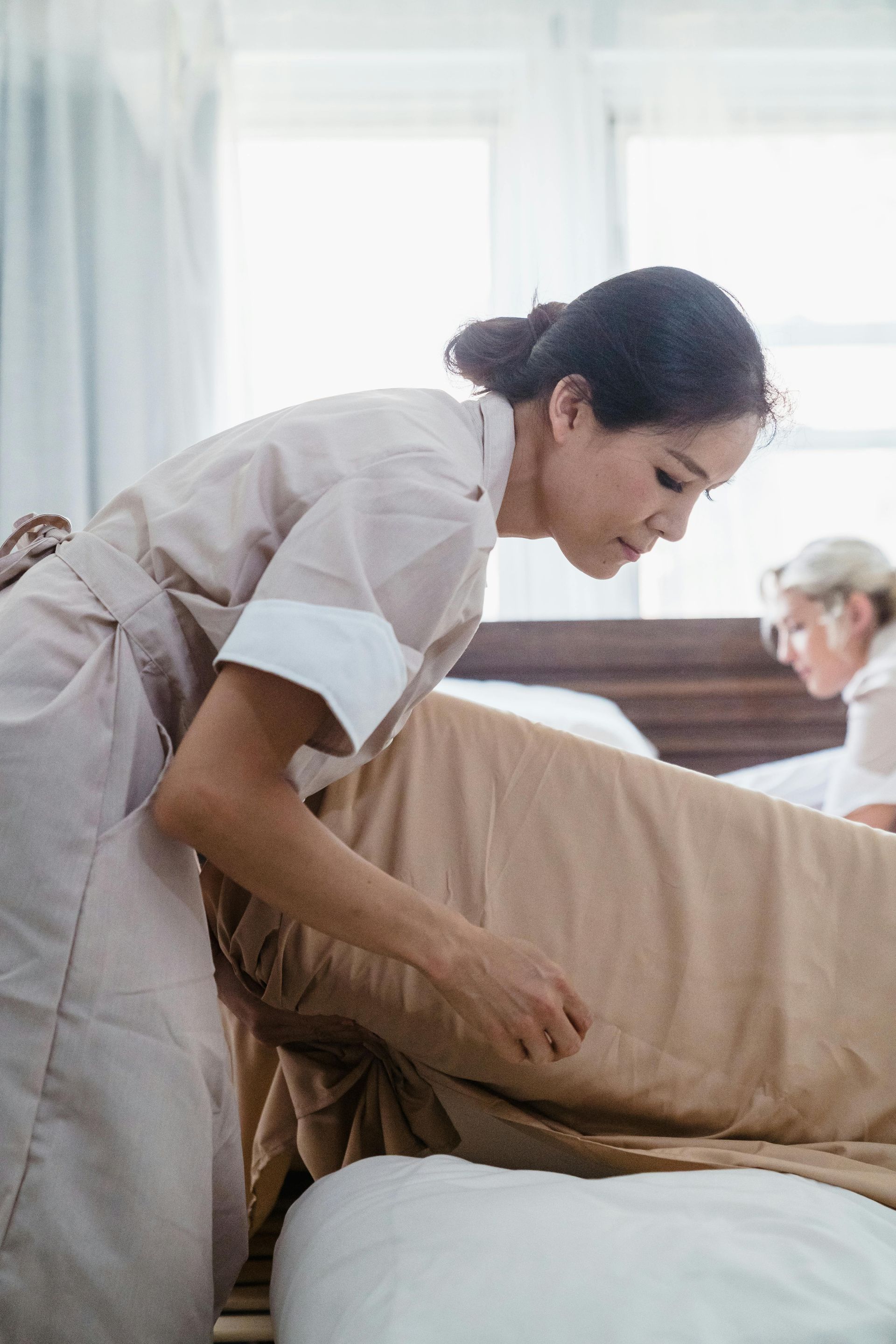 A maid is making a bed for a patient in a hotel.
