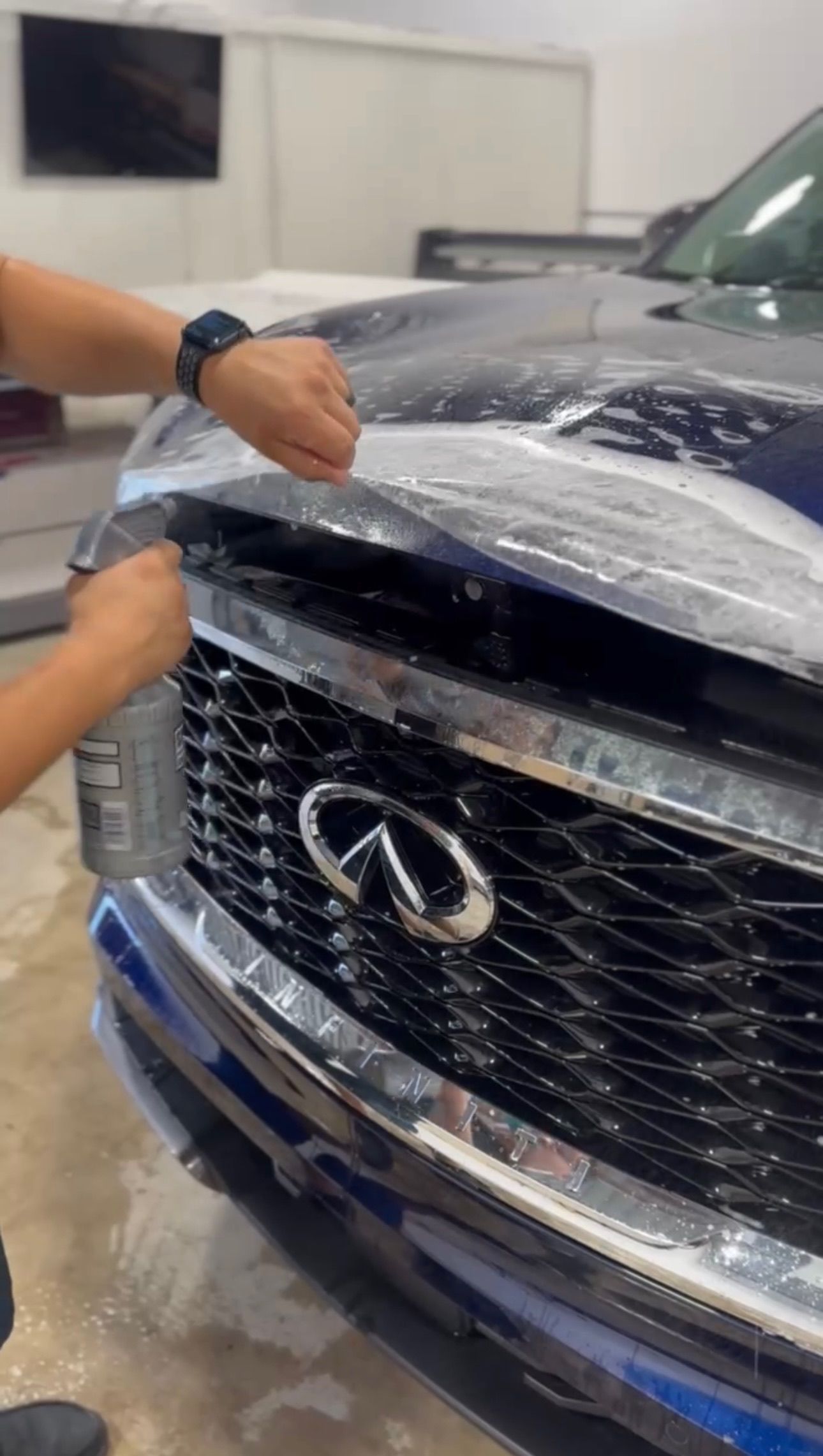 a person is covering the hood of a car with plastic wrap .
