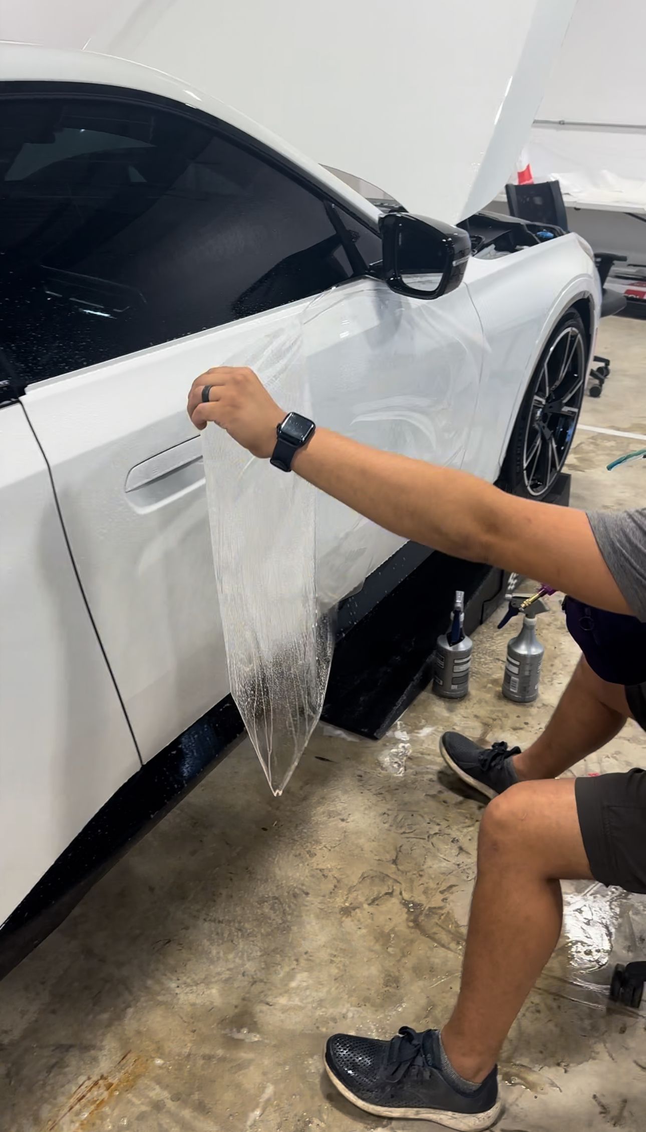a man is wrapping a white car with plastic wrap .