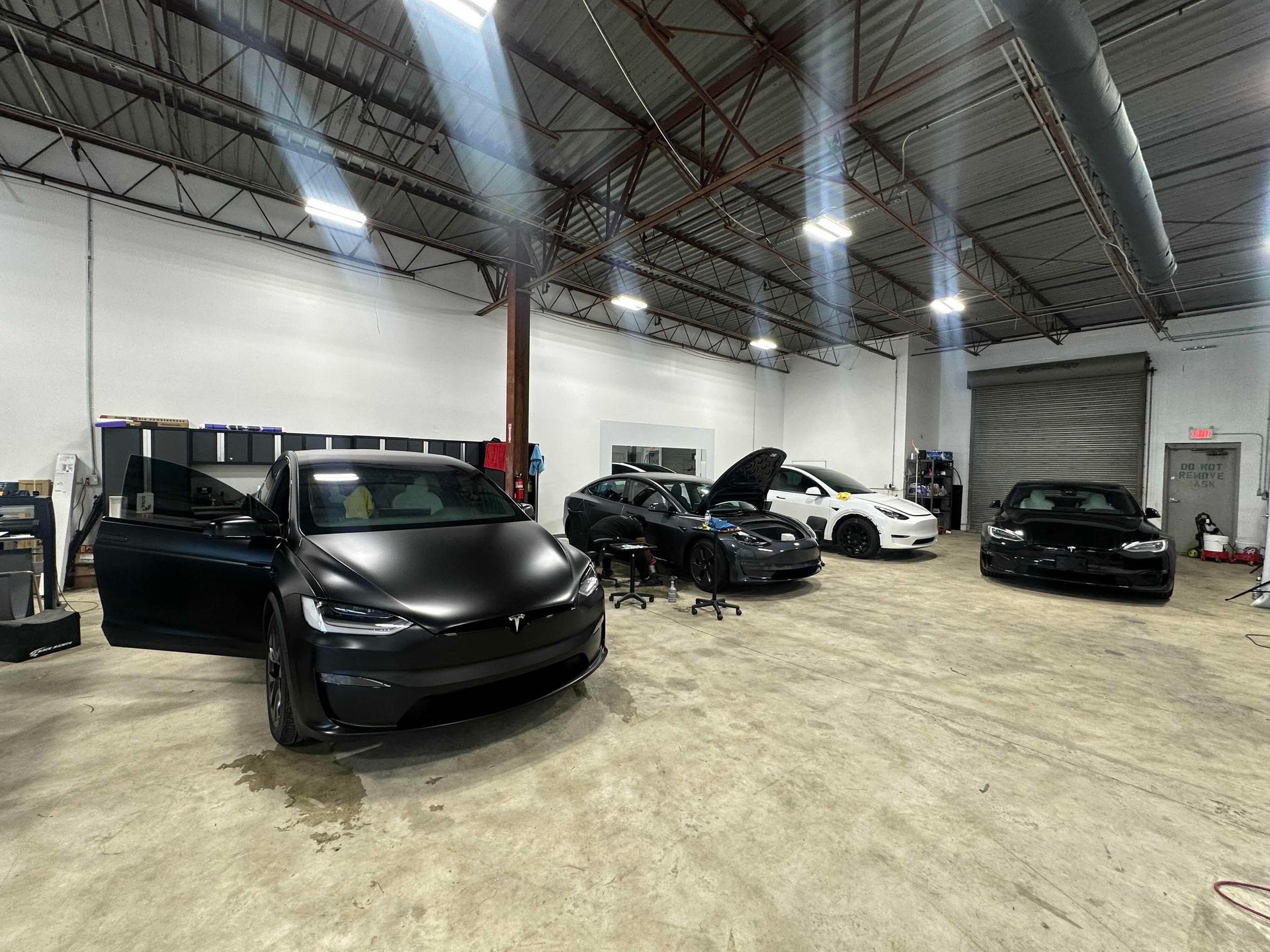 a tesla model s is parked in a garage with other cars .