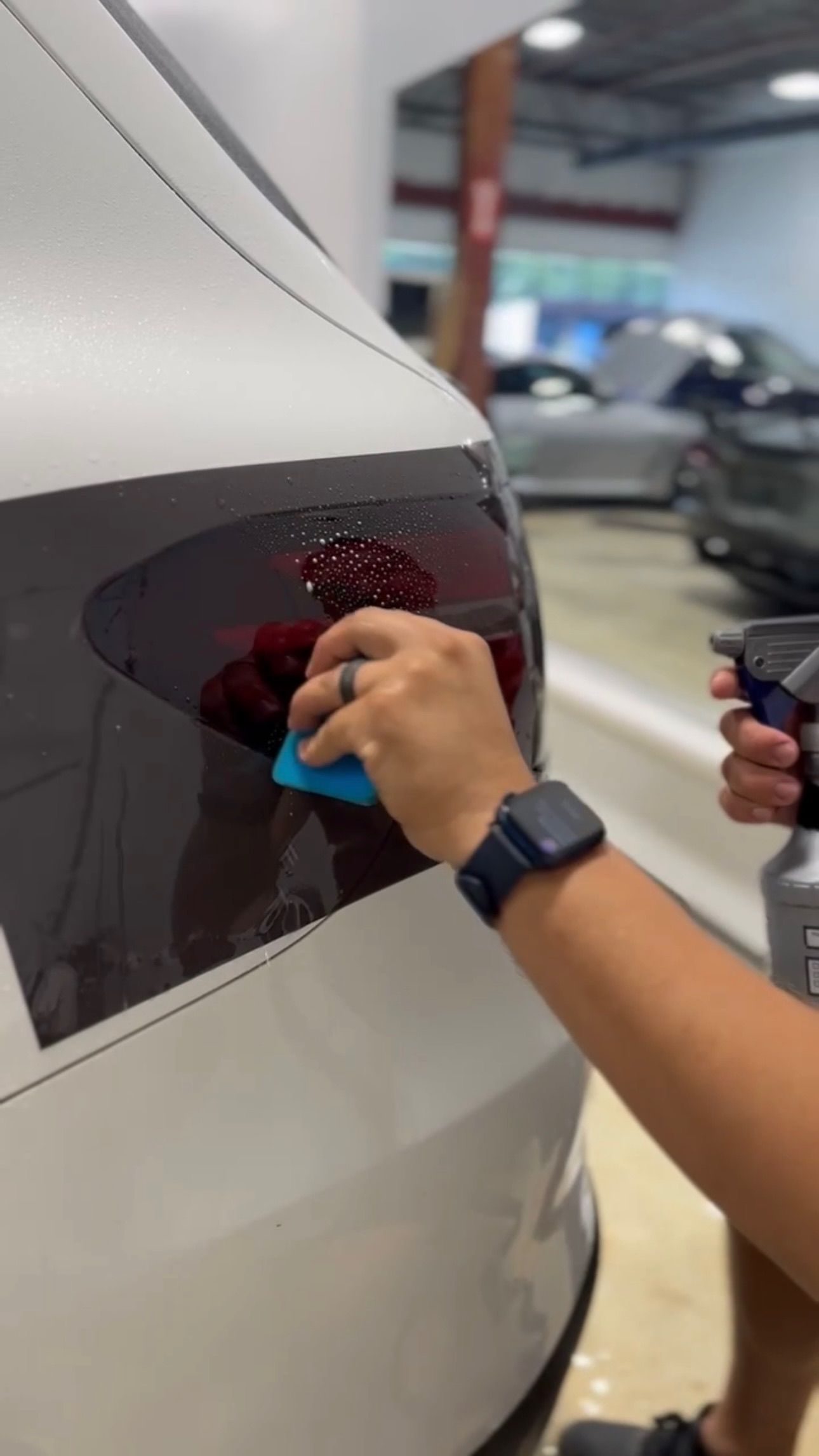 a person is applying a sticker to the back of a car .